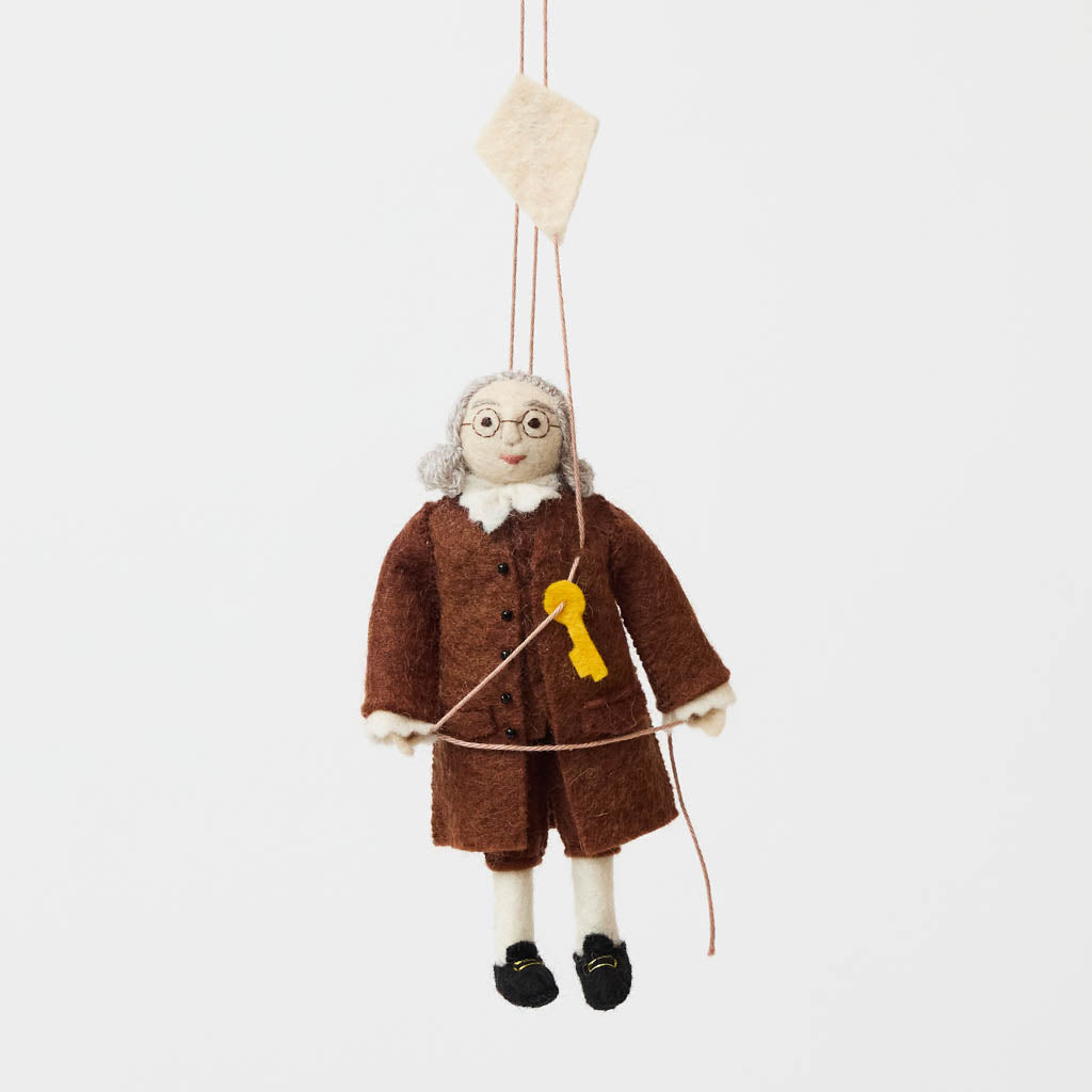 Honor the brilliance and ingenuity of a true American icon with our handcrafted Benjamin Franklin Ornament from the Craftspring Semiquincentennial Collection. Featuring Franklin in his classic colonial attire while flying a kite with a key