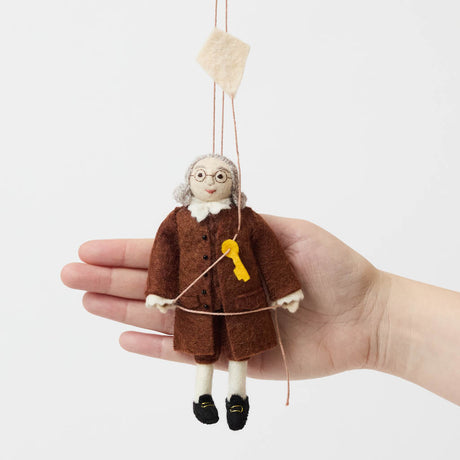 Honor the brilliance and ingenuity of a true American icon with our handcrafted Benjamin Franklin Ornament from the Craftspring Semiquincentennial Collection. Featuring Franklin in his classic colonial attire while flying a kite with a key