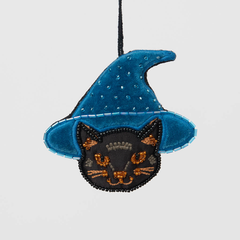 A double-sided handmade Black Cat Beaded Ornament featuring an intricately embroidered cat in a sparkling blue witch hat, with a playful “Boo” on the reverse.