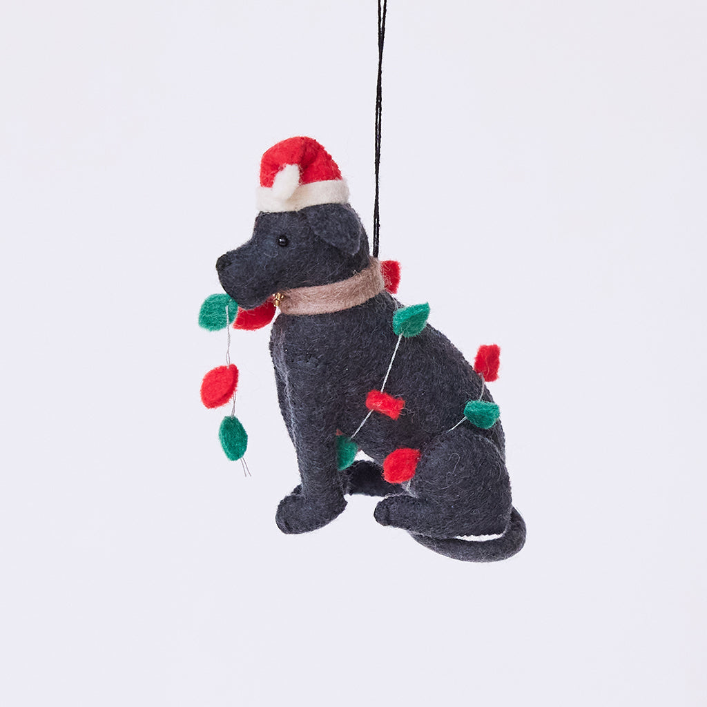 Craftspring’s Black Lab in Christmas Lights Ornament — felt dog wrapped in Christmas lights and wearing a Santa hat, cute and festive — heirloom-quality Christmas ornament, perfect for holiday gifting, ethically crafted by artisans using sustainable wool.