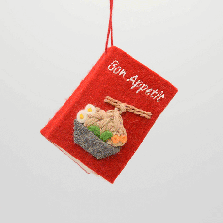 Handmade felt Bon Appetit Cookbook ornament from Craftspring spinning to show front, side, and back covers—featuring embroidered details inspired by cooking and recipes, ethically crafted by artisans using sustainable wool.