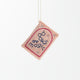 Hot pink felt ornament shaped like a small book, featuring delicately embroidered open pages. Inspired by the beloved Brooklyn bookstore Books Are Magic, this hand-felted wool ornament includes a hanging string and measures approximately 2.5 inches tall. A colorful tribute to the joy of reading and storytelling