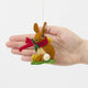 Our Brown Holiday Bunny with Chick Ornament is a sweet story of kindness and holiday cheer. Wrapped in a cozy crimson scarf adorned with felt holly and tiny red beads, this gentle brown bunny sits besides fluffy yellow chicks and a freshly hatched egg, capturing the magic of winter and the simple joy of being together.