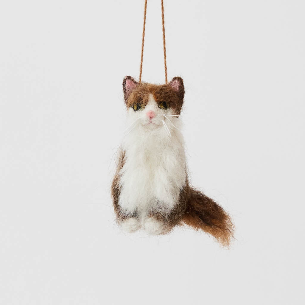 Celebrate the unique beauty of feline companions with our felt Calico Cat Ornament. Carefully handcrafted by skilled artisans, this elegant ornament features the signature patchwork of warm browns, soft whites, and golden tones that make calico cats so beloved.