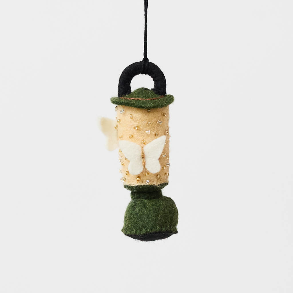 Handcrafted from natural wool felt, this charming vintage-inspired lantern features soft ivory tones accented with shimmering golden beadwork that mimics the gentle glow of lantern light. Delicate felt moths flutter around the lantern, adding a whimsical touch that captures the quiet magic of nature at dusk. Rich forest green details complete the design, making it a timeless keepsake for campers, hikers, glampers, and outdoor dreamers alike.