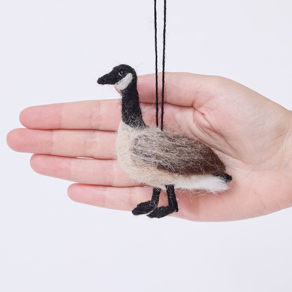 Craftspring’s Canada Goose Ornament displayed in front of a hand to show its size — needle felted with soft wings and beaded eyes, a sweet heirloom-quality piece to celebrate the joy of Christmas gifting — ethically crafted by artisans using sustainable wool.