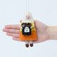 Craftspring’s Candy Corn Trick-or-Treater Ornament in front of a hand to show its size—handmade from sustainable wool with a beaded candy corn costume and a bag of beaded and embroidered candy, ethically crafted by artisans using sustainable wool.