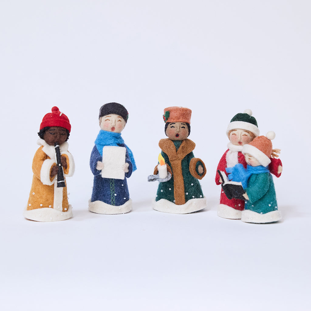 Handmade felt Carolers Set of 5 ornaments from Craftspring, featuring four singers and one clarinet player dressed in vintage clothes, with applique and embroidered snow at their feet — sweet-faced holiday decor that can stand on a mantle or hang on a Christmas tree, ethically crafted by artisans using sustainable wool.