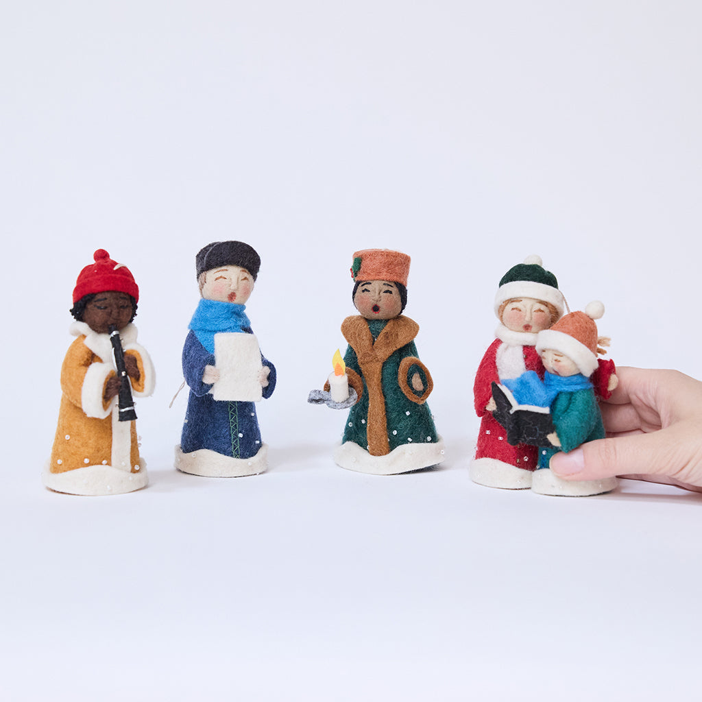 One caroler ornament from Craftspring’s Carolers Set of 5 held in hand to show its size — handmade felt holiday decor with sweet embroidered details and applique snow, ethically crafted by artisans using sustainable wool.
