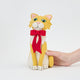 Handmade felt Orange Cat Tree Topper from Craftspring held in hand to show size—featuring a festive red bow and detailed stitching, showcasing heirloom-quality holiday decor, ethically crafted by artisans using sustainable wool.