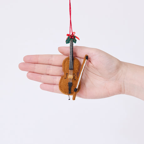 Craftspring’s Cello Ornament displayed in front of a hand to show its size — handmade from sustainable wool with a bow, holly, and detailed embroidery, ethically crafted by artisans using sustainable wool.