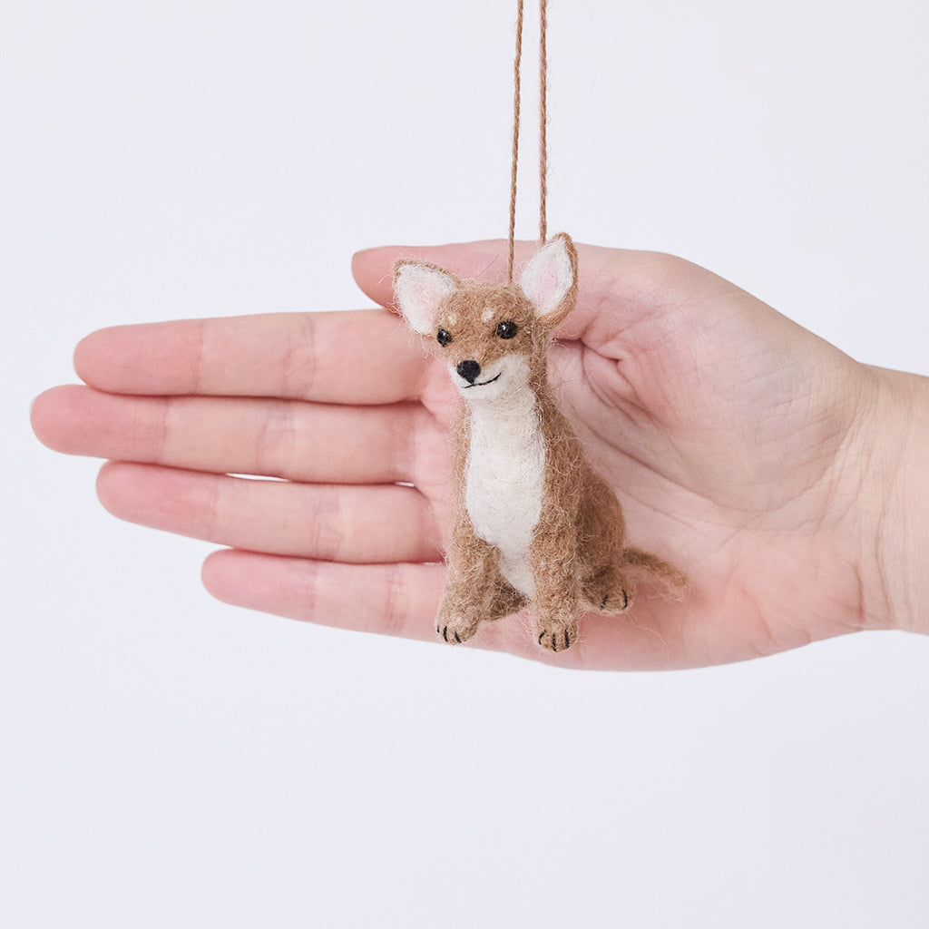 Craftspring’s Chihuahua Ornament displayed in front of a hand to show its size—needle-felted with big ears and a charming face, ethically crafted by artisans using sustainable wool.