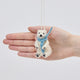 Handmade needle-felted Chilly Polar Bear ornament from Craftspring held in front of a hand to show its size—featuring a cozy blue scarf and detailed needle felting, ethically crafted by artisans using sustainable wool.