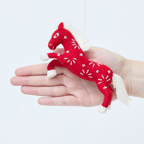 Craftspring’s Chinese Red Horse Ornament shown in front of a hand to display its size — handmade from sustainable wool with intricate beaded and embroidered Lunar New Year details, ethically crafted by artisans using sustainable wool.