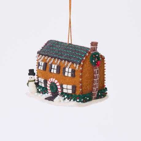 Craftspring’s Christmas House Ornament — felt house covered in intricate details with beading, embroidery, and applique, featuring a snowman in the yard, beaded icicles hanging from the roof, and holly bushes around the house — heirloom-quality Christmas ornament, perfect for holiday gifting, ethically crafted by artisans using sustainable wool.