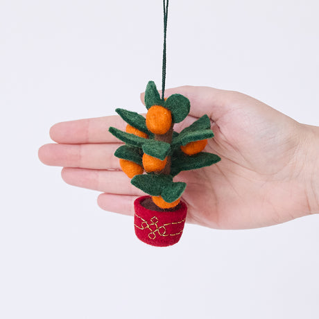 Craftspring’s Clementine Tree Ornament displayed in front of a hand to show its size — handmade from sustainable wool with a red embroidered pot and eight clementines, ethically crafted by artisans for festive Christmas and Lunar New Year gifting.