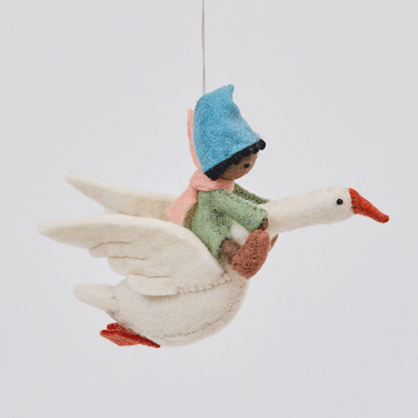 Handmade felt Cloud Dancer Dream Goose ornament – Brown – from Craftspring rotating to show front, side, and back views—featuring a detailed baby with brown skin and black hair riding a white goose, showcasing artisan craftsmanship and intricate stitching, ethically crafted using sustainable wool.
