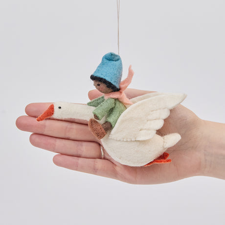 Handmade felt Cloud Dancer Dream Goose Ornament – Brown from Craftspring held in front of a hand to show its size—featuring a detailed baby with brown skin and black hair riding a white goose, showcasing artisan craftsmanship and perfect for nursery decor and thoughtful gifting, ethically crafted using sustainable wool.