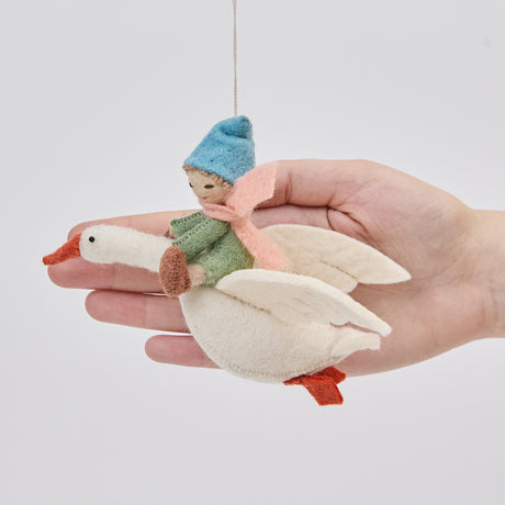 Handmade felt Cloud Dancer Dream Goose Ornament – Light from Craftspring held in front of a hand to show size—featuring a detailed baby with light skin and blonde hair riding a flying white goose, perfect for nursery decor and thoughtful gifting, ethically crafted using sustainable wool.