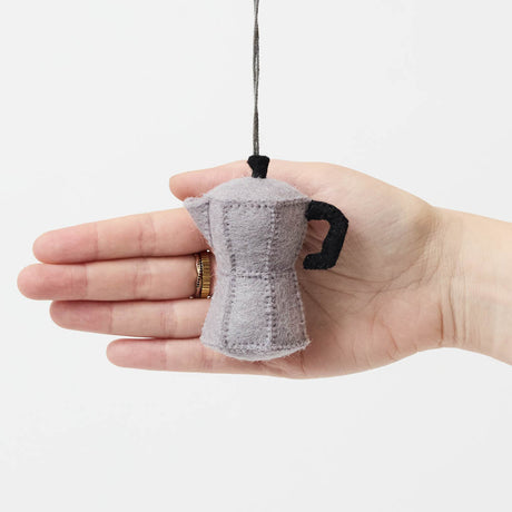 Handcrafted from natural wool felt, this charming ornament is inspired by the classic stovetop camping percolator—a beloved companion for generations of campers, hikers, RV travelers, and cabin lovers. Its timeless silhouette, soft neutral tones, and handcrafted stitching evoke memories of peaceful mornings surrounded by towering pines, fresh mountain air, and the sounds of nature waking up.