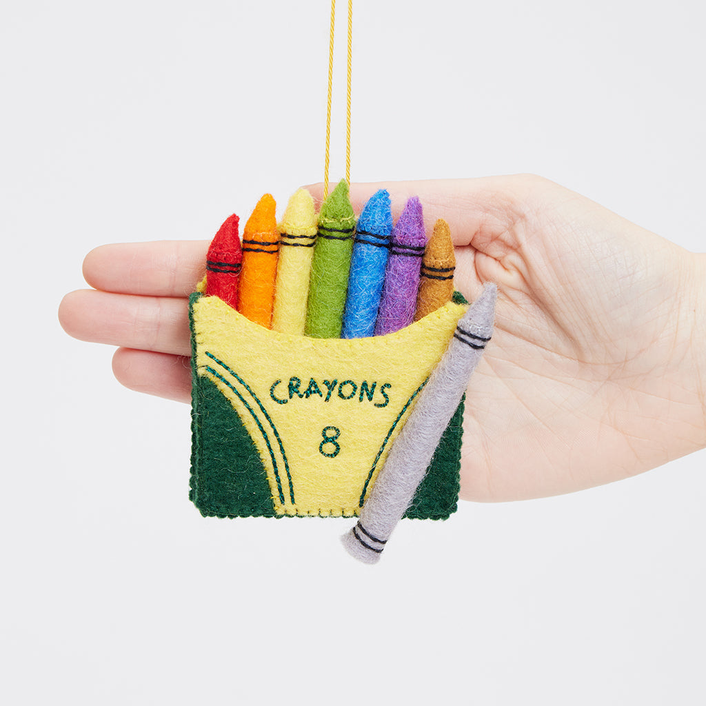 Felt crayon box ornament with colorful details, handmade and fair trade.

