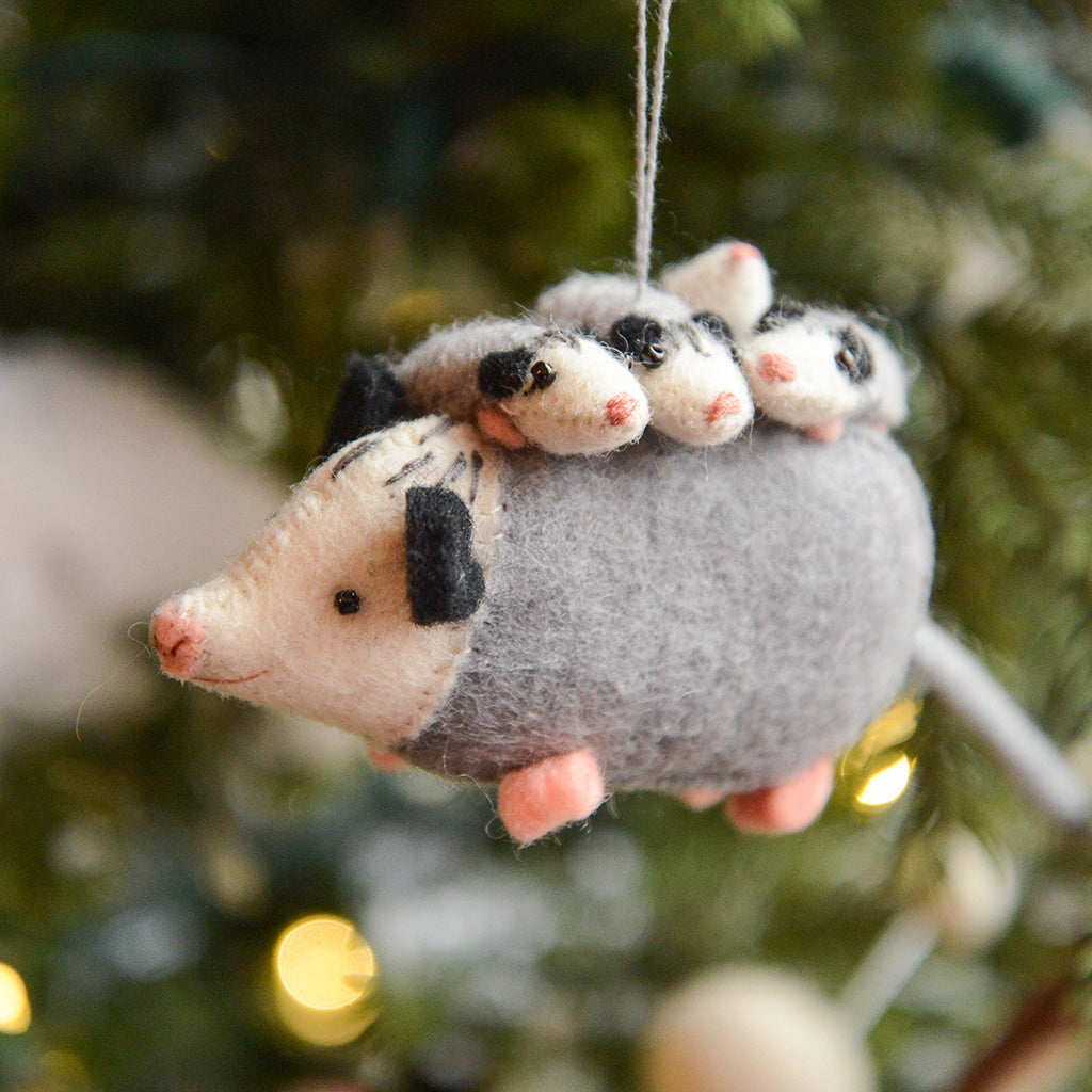 Handmade felt Opossum Mom with Babies Ornament from Craftspring hanging on a Christmas tree—mama opossum with cute babies on her back, embroidered and beaded details, heirloom-quality holiday decor ethically crafted by artisans using sustainable wool.