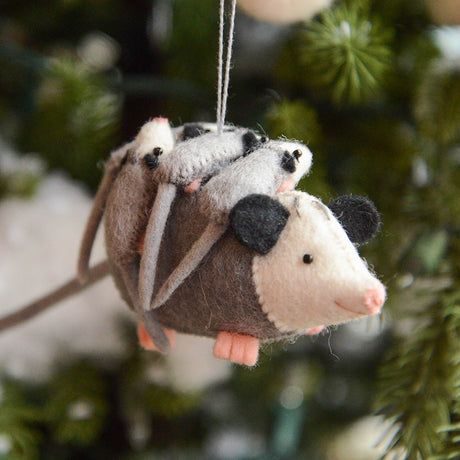Handmade felt Opossum Mom with Babies Ornament from Craftspring hanging on a Christmas tree—mama opossum with cute babies on her back, embroidered and beaded details, heirloom-quality holiday decor ethically crafted by artisans using sustainable wool.