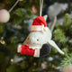 Craftspring’s Jolly Santa Shark with Santa Leg Ornament — a playful shark wearing a Santa hat and holding Santa’s leg in its mouth, with beaded and embroidered holiday details — displayed on a glowing Christmas tree, bringing humorous, joy-filled warmth to festive decorating and holiday gifting, ethically crafted by artisans using sustainable wool.