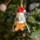 Craftspring’s Jolly Santa Shark with Gingerbread Ornament — a playful shark holding a gingerbread man in its teeth with beaded and embroidered holiday details — displayed on a glowing Christmas tree, bringing humorous, joy-filled warmth to festive decorating and holiday gifting, ethically crafted by artisans using sustainable wool.