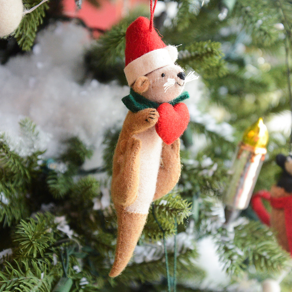 Craftspring’s Santa Otter Love Ornament — a sweet otter wearing a Santa hat and holding a heart, detailed with soft embroidered holiday accents — displayed on a glowing Christmas tree, bringing warm, whimsical charm and gift-ready Christmas joy to festive decorating, ethically crafted by artisans using sustainable wool.
