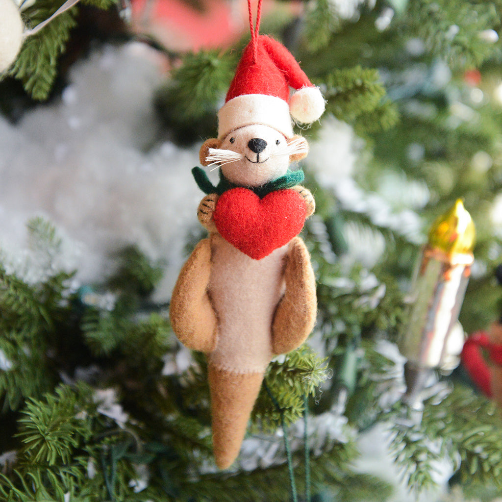 Craftspring’s Santa Otter Love Ornament — a sweet otter wearing a Santa hat and holding a heart, detailed with soft embroidered holiday accents — displayed on a glowing Christmas tree, bringing warm, whimsical charm and gift-ready Christmas joy to festive decorating, ethically crafted by artisans using sustainable wool.