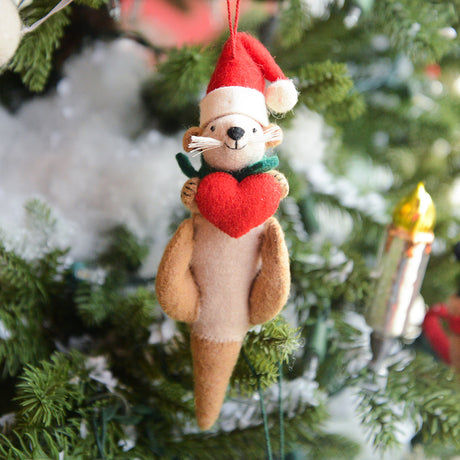 Craftspring’s Santa Otter Love Ornament — a sweet otter wearing a Santa hat and holding a heart, detailed with soft embroidered holiday accents — displayed on a glowing Christmas tree, bringing warm, whimsical charm and gift-ready Christmas joy to festive decorating, ethically crafted by artisans using sustainable wool.