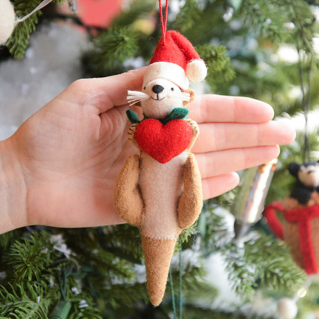 Craftspring’s Santa Otter Love Ornament displayed in front of a hand to show its size — featuring a Santa hat and a heart held close with embroidered details — a cute, heirloom-quality treasure perfect for meaningful Christmas gifting, ethically crafted by artisans using sustainable wool.