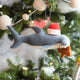 Craftspring’s Take a Bite Out of Christmas Hammerhead Ornament — a festive hammerhead shark wearing a Santa hat and munching a gingerbread man, detailed with beaded and embroidered holiday accents — displayed on a glowing Christmas tree, adding humorous charm, heirloom-quality warmth, and gift-ready Christmas cheer, ethically crafted by artisans using sustainable wool.