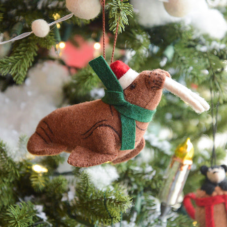 Craftspring’s Santa Walrus Ornament — a charming walrus wearing a Santa hat and a cozy holiday scarf with embroidered details — displayed on a glowing Christmas tree, bringing whimsical warmth, festive delight, and gift-ready Christmas cheer, ethically crafted by artisans using sustainable wool.