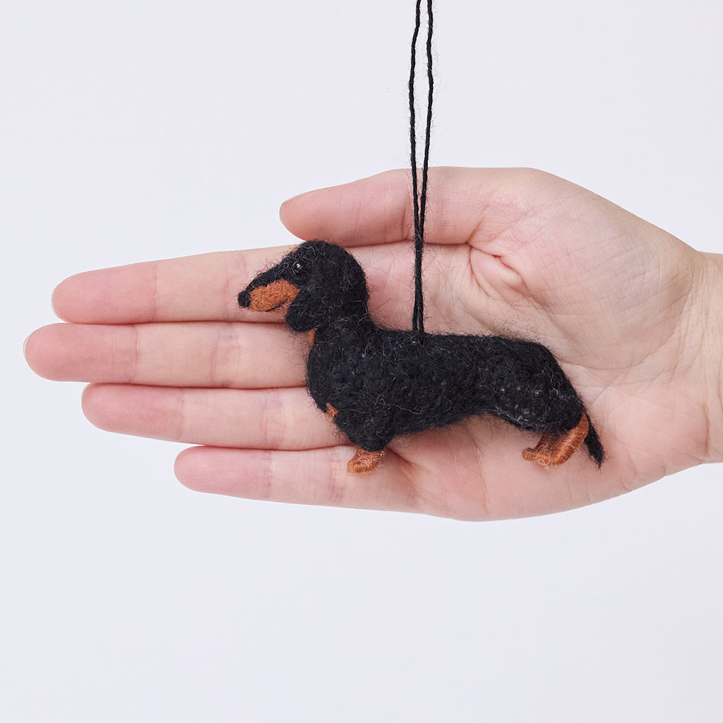 Craftspring’s Dachshund Ornament held in hand to show its size—needle-felted with short legs and a charming face, ethically crafted by artisans using sustainable wool.