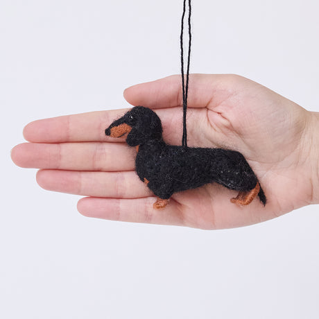 Craftspring’s Dachshund Ornament held in hand to show its size—needle-felted with short legs and a charming face, ethically crafted by artisans using sustainable wool.