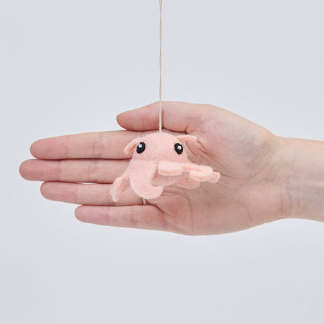 Handmade felt Dumbo Octopus ornament from Craftspring held in front of a hand to show its size—featuring charming curly pink tentacles and detailed embroidery, ethically crafted by artisans using sustainable wool.
