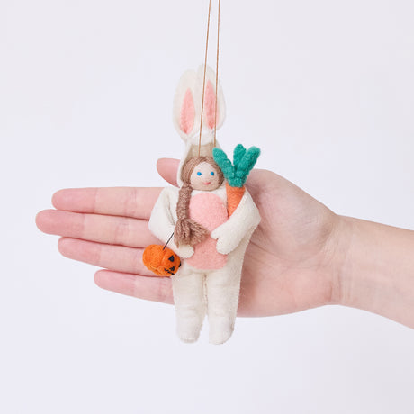 Craftspring’s Easter Bunny Trick-Or-Treater ornament held in front of a hand to show its size—handmade from sustainable wool, featuring a girl in an Easter Bunny costume with a pumpkin basket, ethically crafted by artisans using sustainable wool.