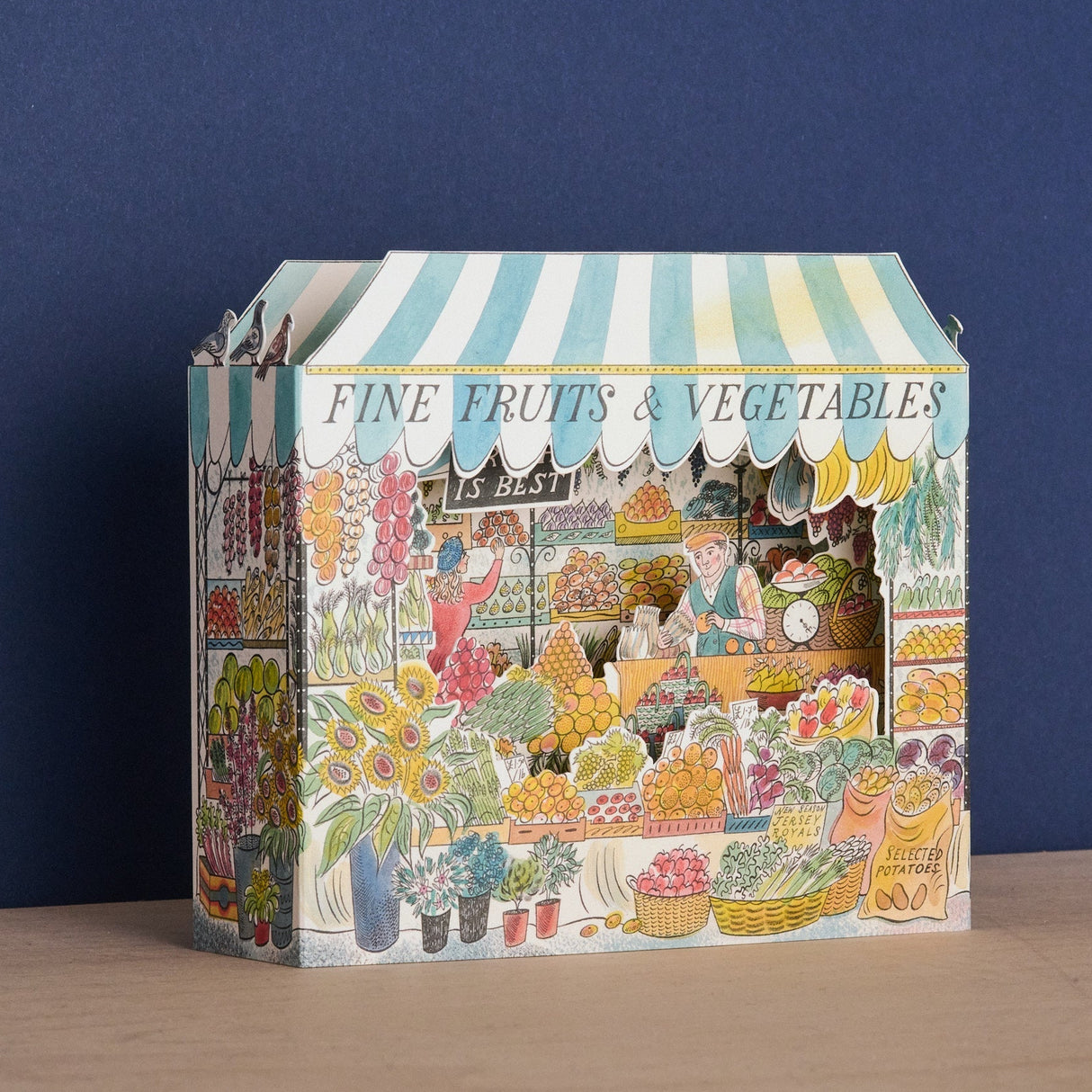 Celebrate the bounty and color of the farmer's market stall with this detailed and whimsical 3D card, illustrated by Emily Sutton. This beautiful die-cut design unfolds into a vibrant three-dimensional display of fresh produce. Peek in to discover a colorful world of painted fruits and veggies.&nbsp;