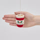 Handmade felt Fa La La Latte ornament from Craftspring held in front of a hand to show its size—featuring detailed embroidery including “Fa la la latte” with holly, a Christmas tree, and a latte heart on top, ethically crafted by artisans using sustainable wool.