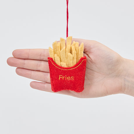 Handmade felt French Fries ornament from Craftspring held in front of a hand to show its size—featuring embroidered details and golden felt fries, ethically crafted by artisans using sustainable wool.