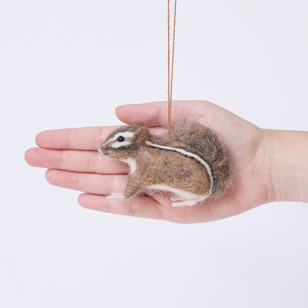 Craftspring’s Fuzzy Chipmunk ornament displayed in front of a hand to show its size — handmade from sustainable wool with stripes along its back and an adorable face, ethically crafted by artisans.