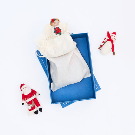 Craftspring blue gift box opened to reveal a cloth bag with handmade felt ornaments peeking out—beautiful, artisan-crafted packaging for heirloom-quality Christmas gifts.