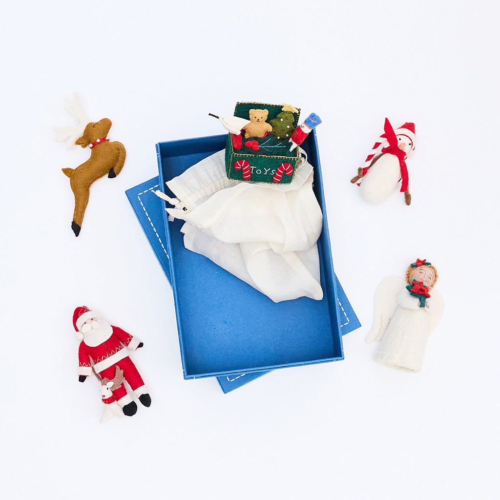 Craftspring blue gift box opened to reveal a cloth bag with handmade felt ornaments peeking out—beautiful, artisan-crafted packaging for heirloom-quality Christmas gifts.