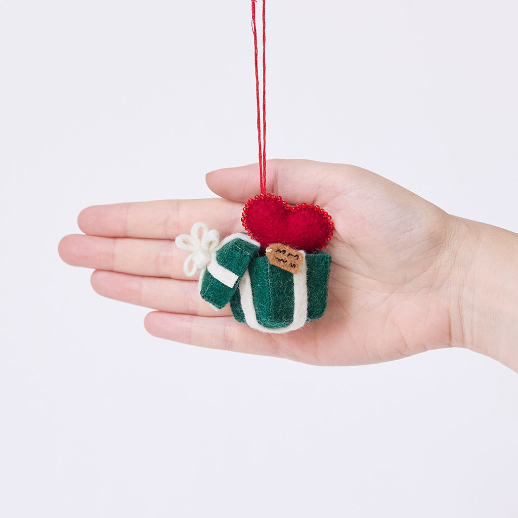Craftspring’s Gift from the Heart Ornament displayed in front of a hand to show its size — felt heart ornament with beaded and embroidered details including a gift tag, perfect for Christmas and holiday gifting, ethically crafted by artisans using sustainable wool.