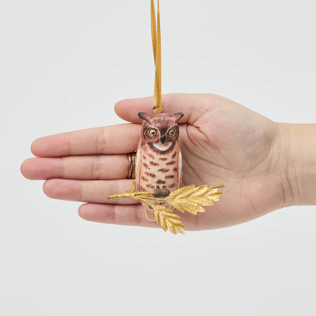 A vintage-inspired Great Horned Owl Resin Ornament, hand-painted in the Philippines and perched on a golden metal oak branch with sculpted leaves.