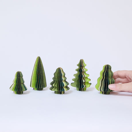 Craftspring’s Green Honeycomb Paper Mini Trees displayed in front of a hand to show scale — Set of 5 with several shades of green, gold sparkle on the edges, and varying shapes, handmade by artisans from recycled cotton waste.