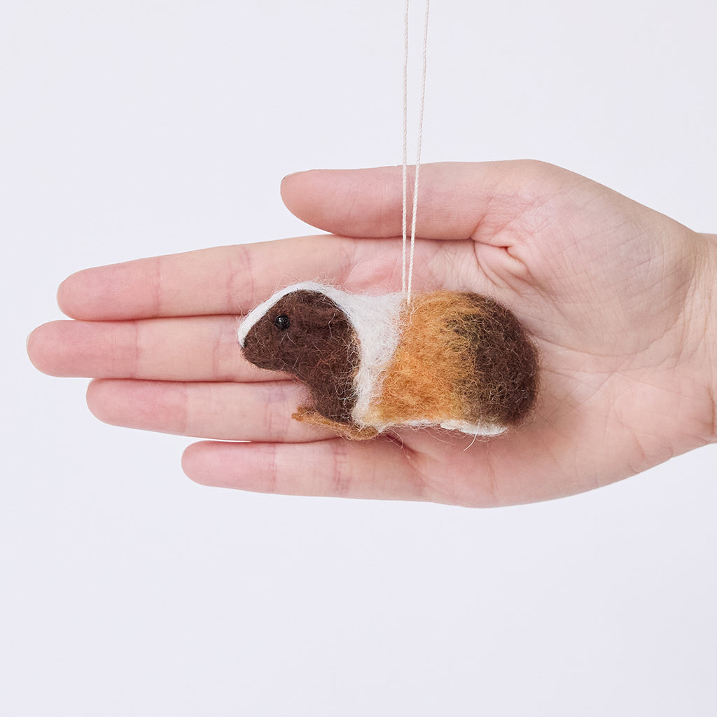 Craftspring’s Guinea Pig Ornament held in hand to show its size—needle felted with charming details and little paws, ethically crafted by artisans using sustainable wool.