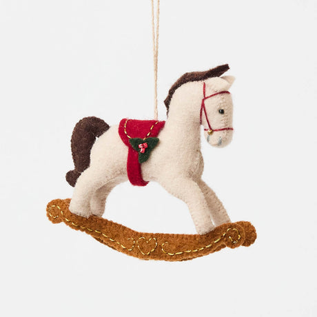 This charming rocking horse ornament captures the magic of childhood and holiday traditions. Crafted from natural wool felt, it features delicate stitching, a soft neutral palette, and subtle festive details that make it perfect for both baby gifting and seasonal décor.